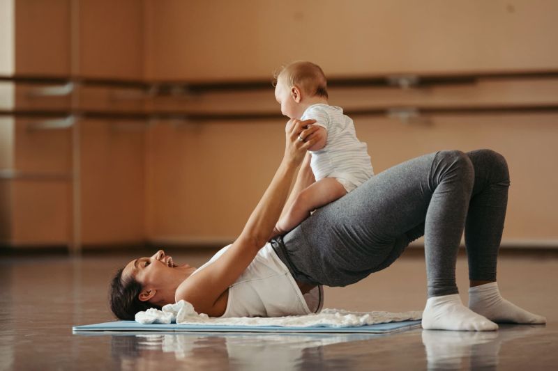 Athletic mother having fun while exercising with her baby